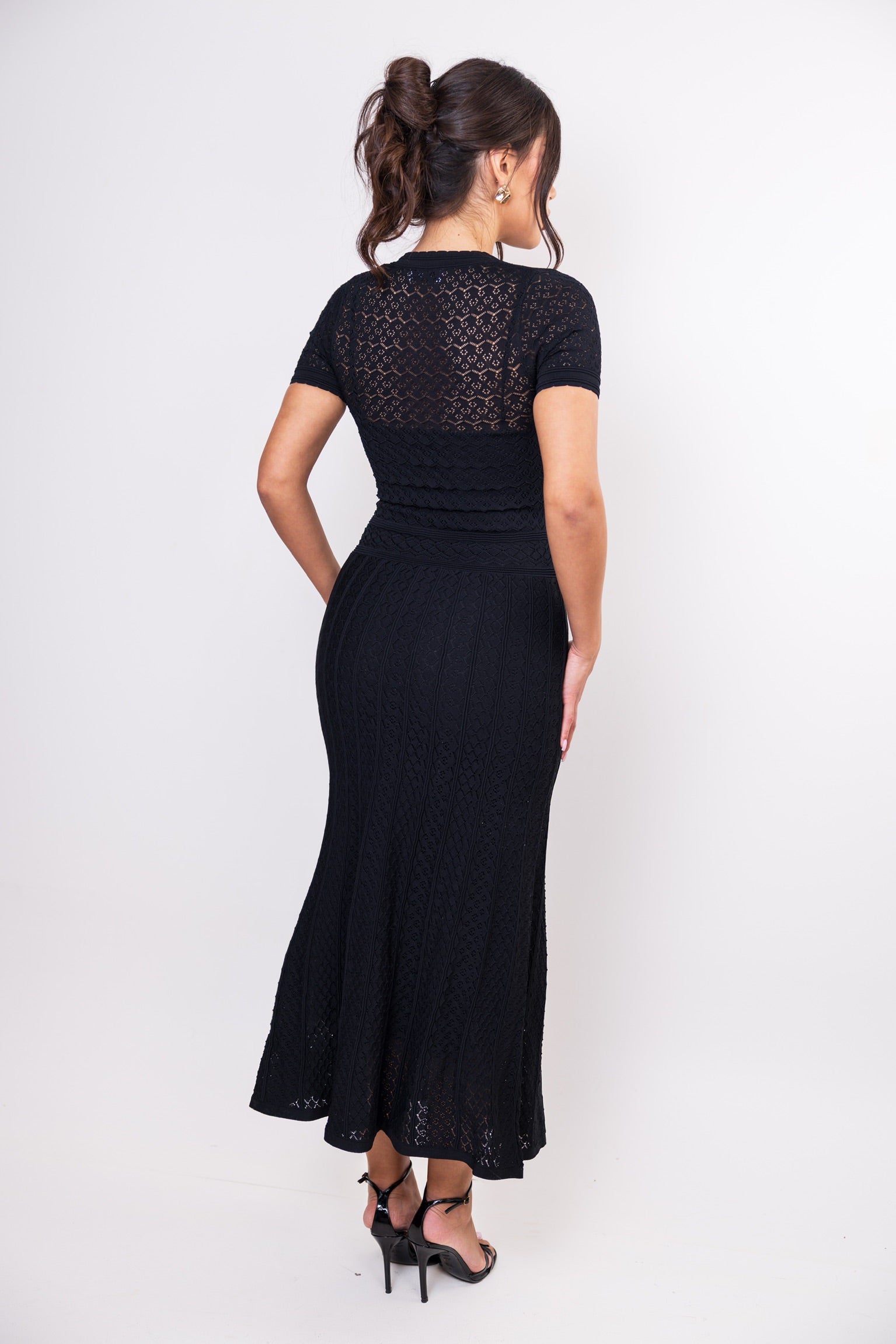 Woman wearing a black dress with lace detailing on a white background