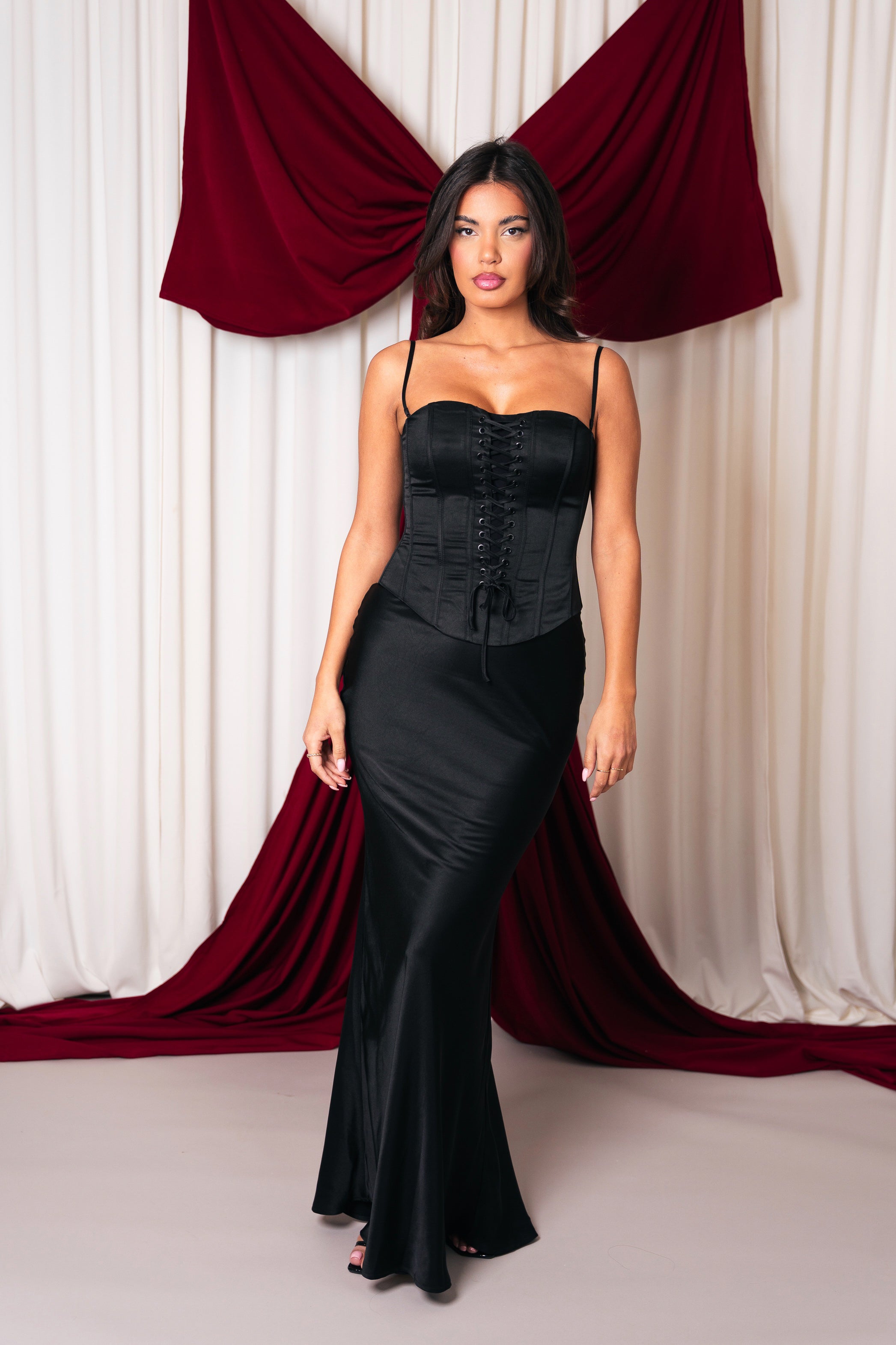 Front view of the Stela dress, emphasizing the waist-cinching corset, feathered sleeves, and long fitted skirt.