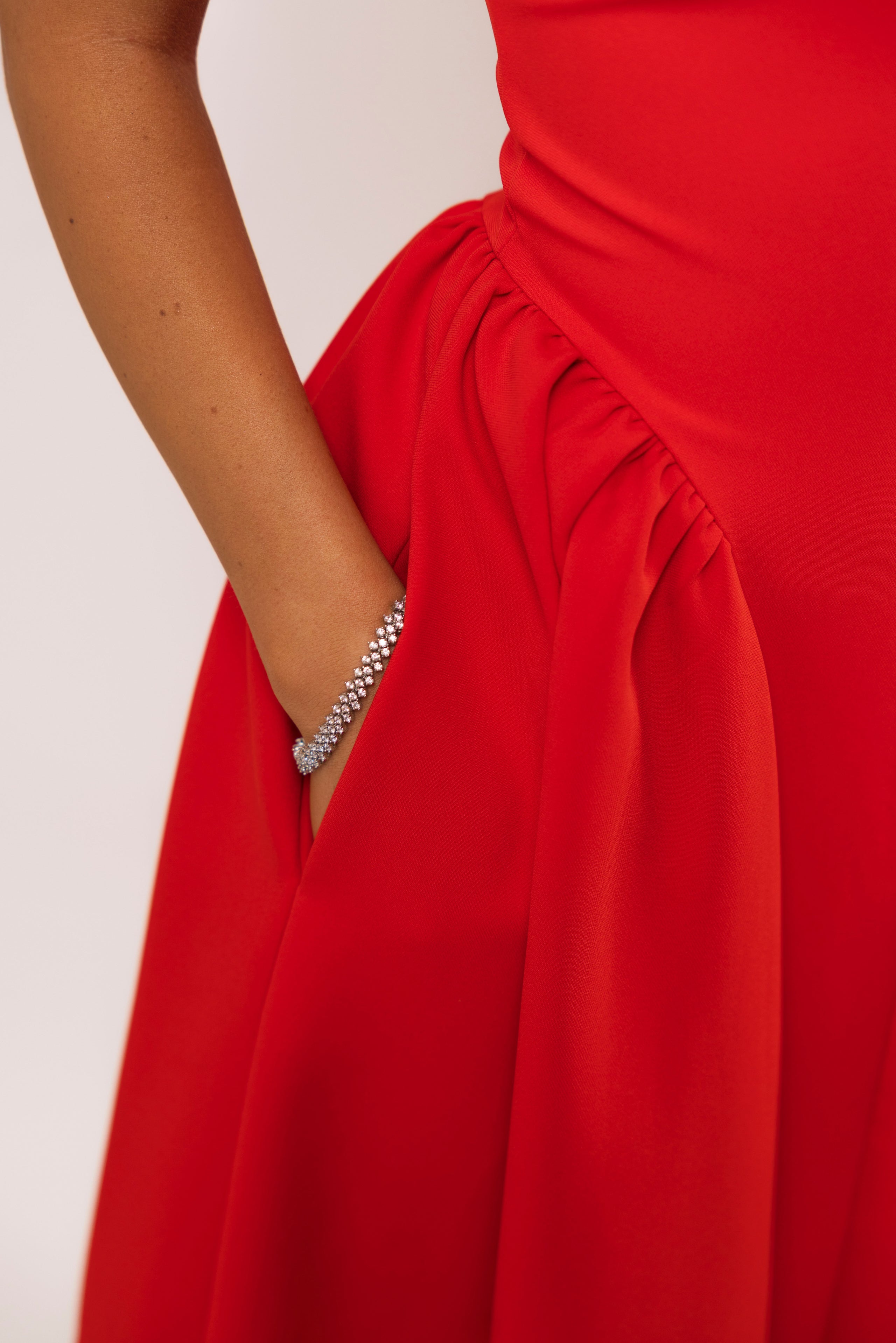 Close-up of red dress featuring gathered waist and crystal button accent.

