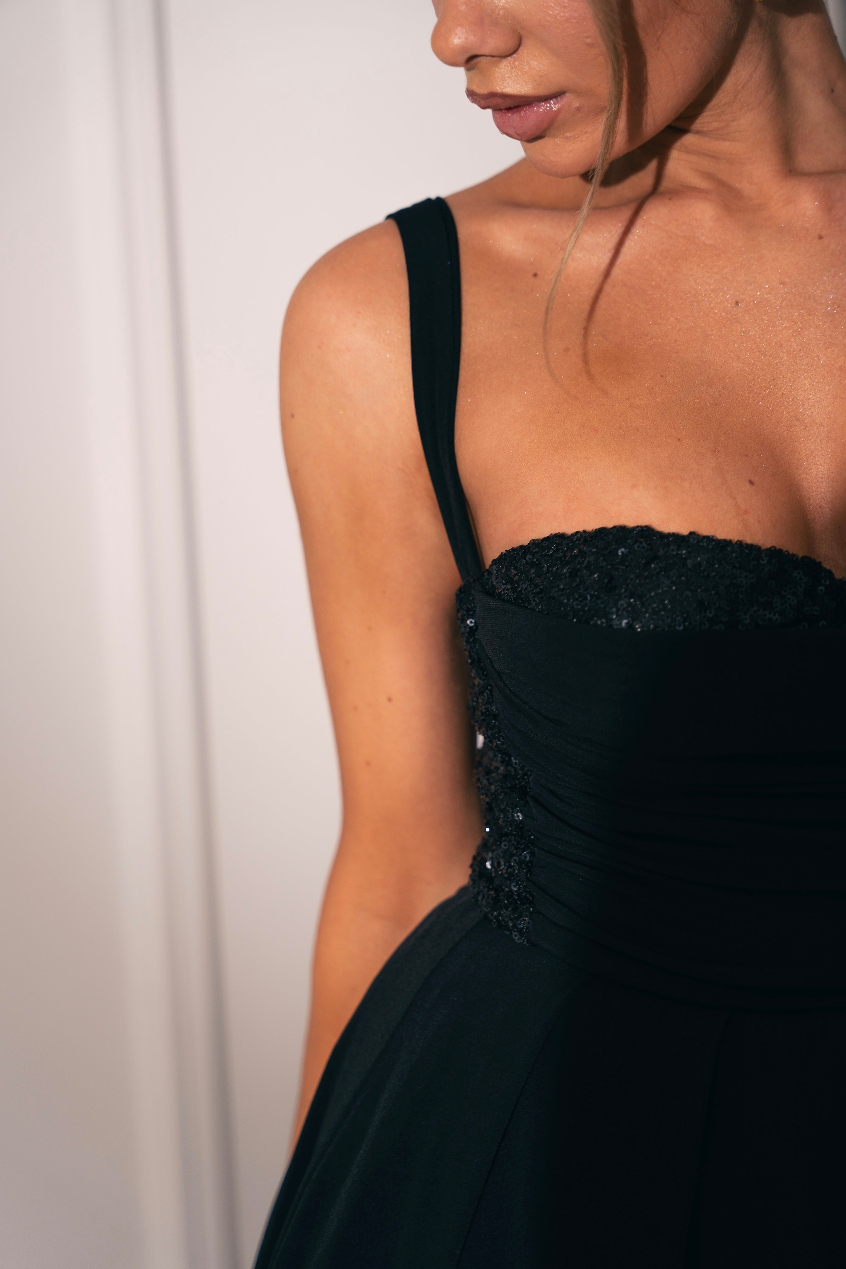 Sophisticated A-line black dress featuring delicate ruching and shoulder straps.