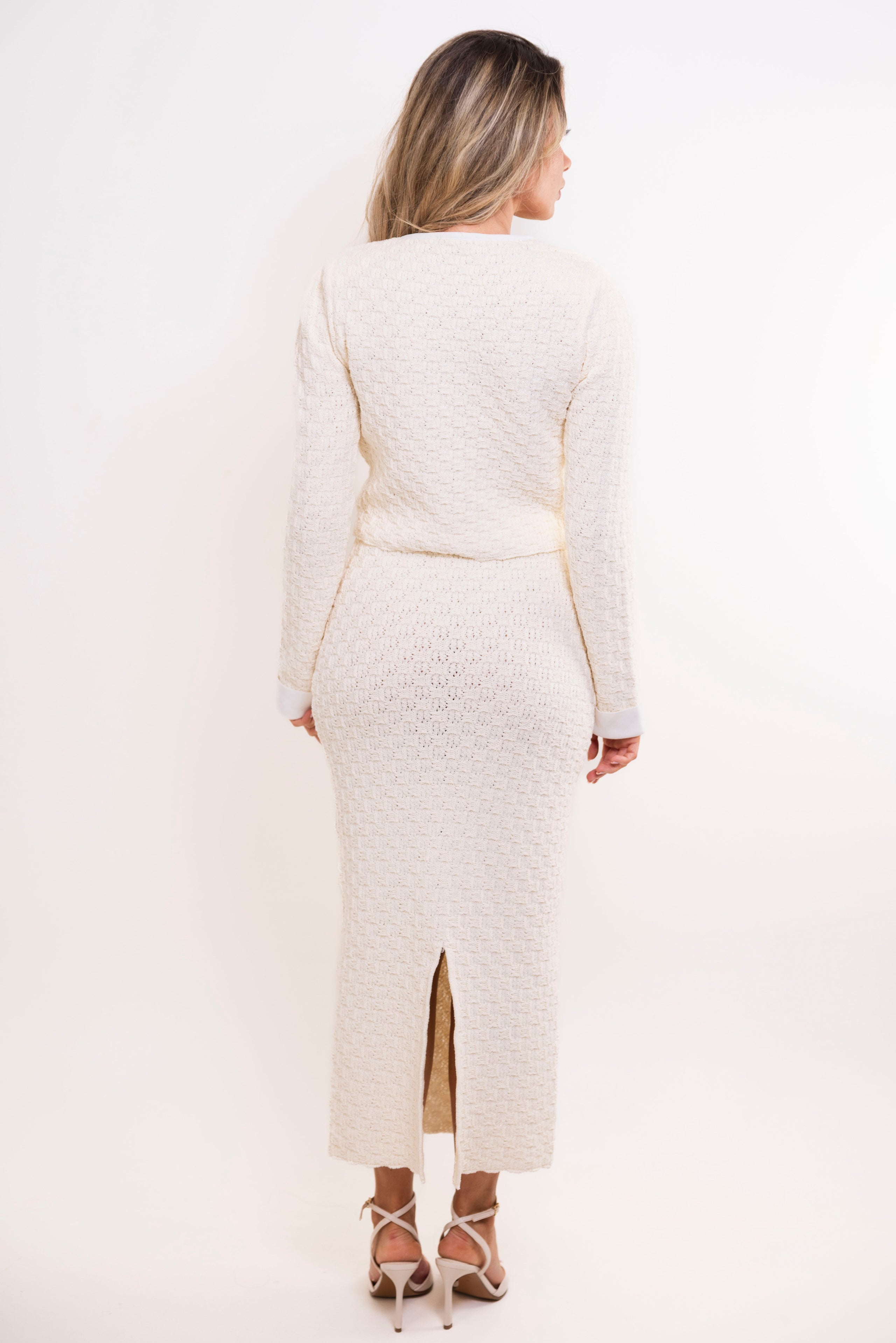 Back view of cream midi skirt with slit and matching knit top.
