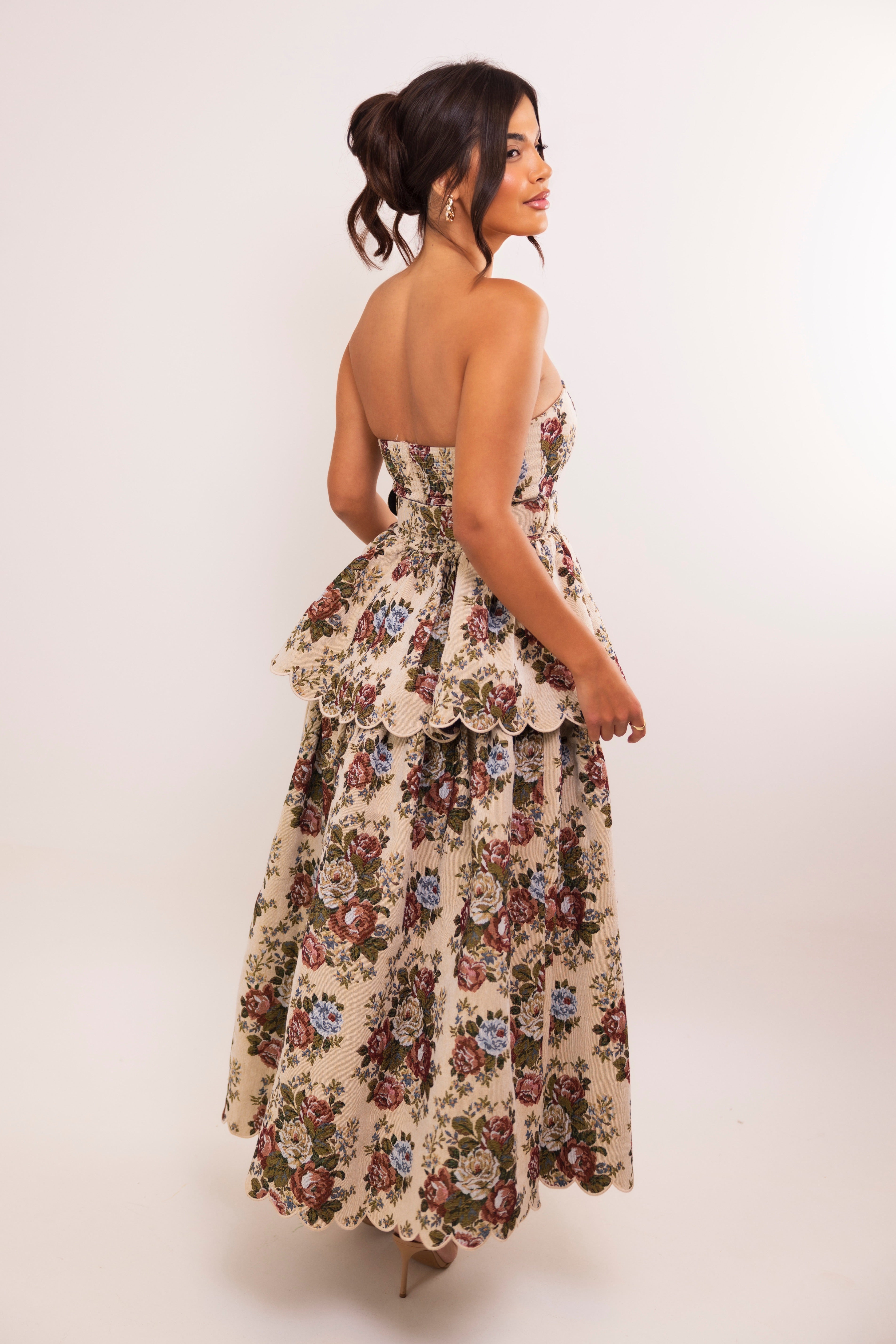 Back view of a strapless floral jacquard gown with scalloped hem and soft pleated volume